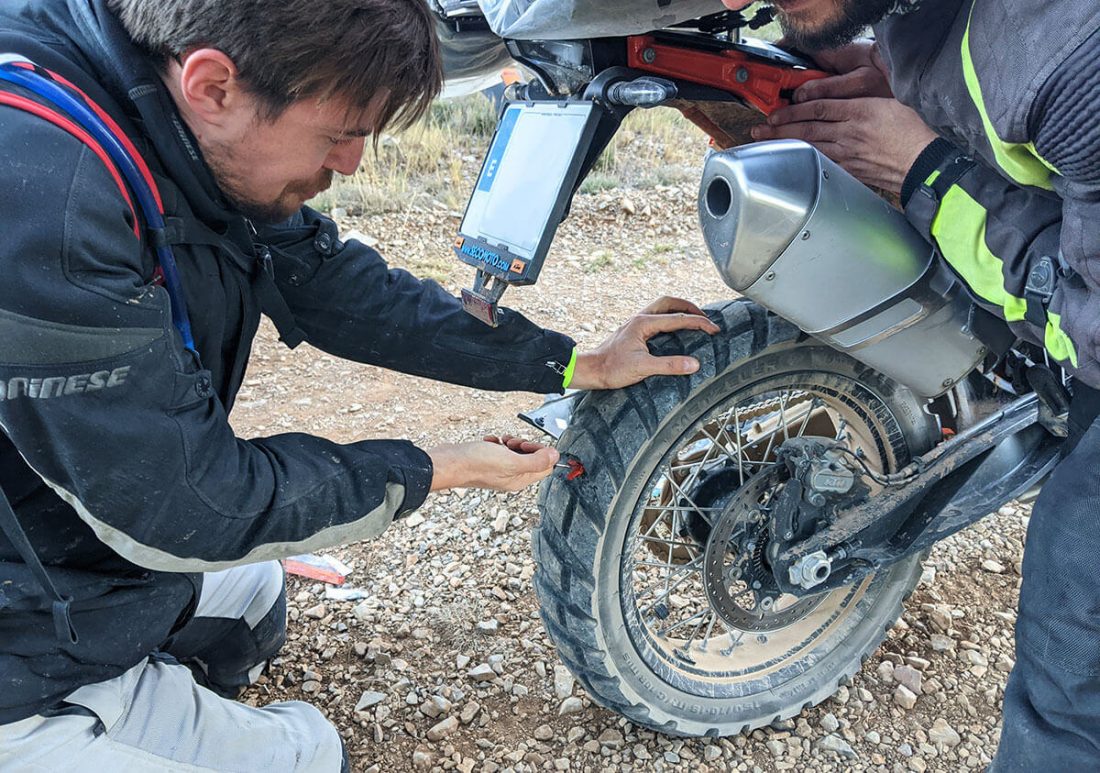 Piloto arreglando pinchazo en rueda trasera a moto KTM 790