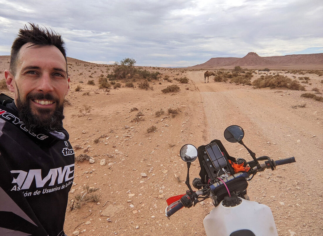 Selfie ante moto y dromedario en la pista en el desierto