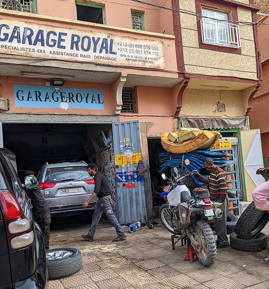 Puerta de un taller con dos coches y una moto.