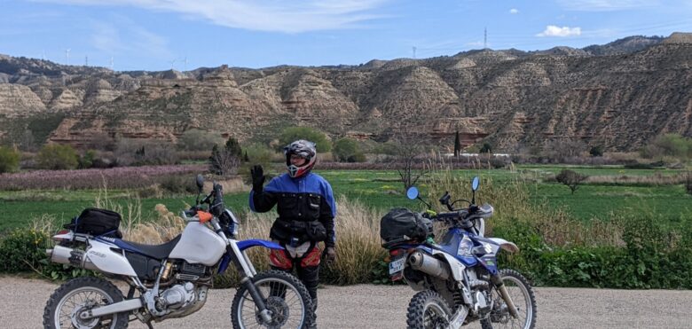 Dos motos y un motero posando ante unas montañas